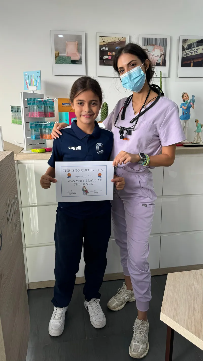 Dr. Rita Kanbar with a young patient holding a bravery certificate