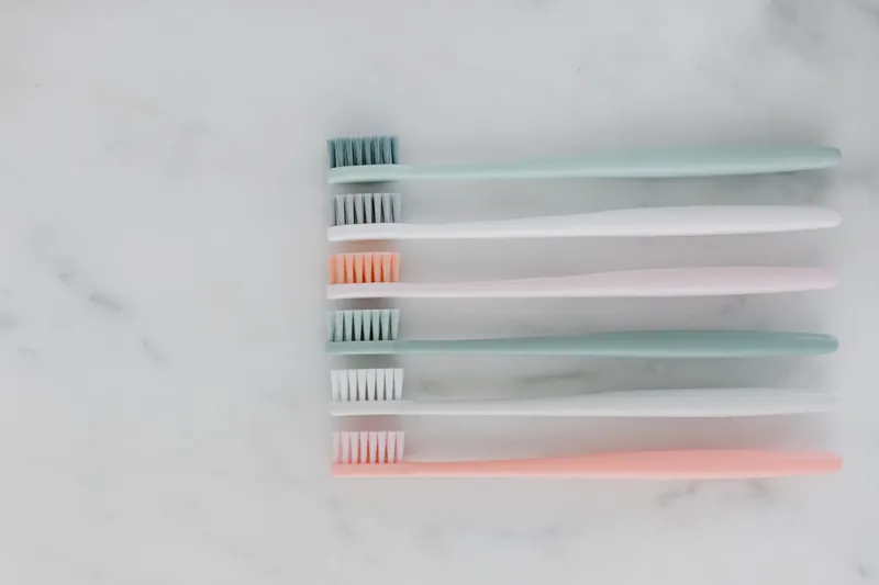 Pastel toothbrushes laid side by side on marble